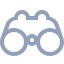 A simple gray icon of binoculars on a light background, viewed from the front, featuring two large circular lenses and two smaller circles at the top representing the eyepieces.